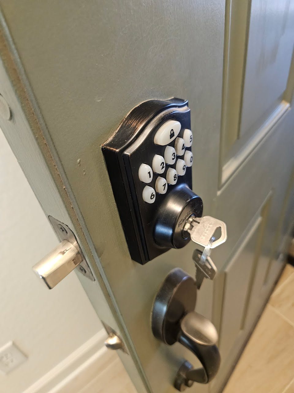 Keypad deadbolt with lever handleset installed on a home entry door, keys in the lock